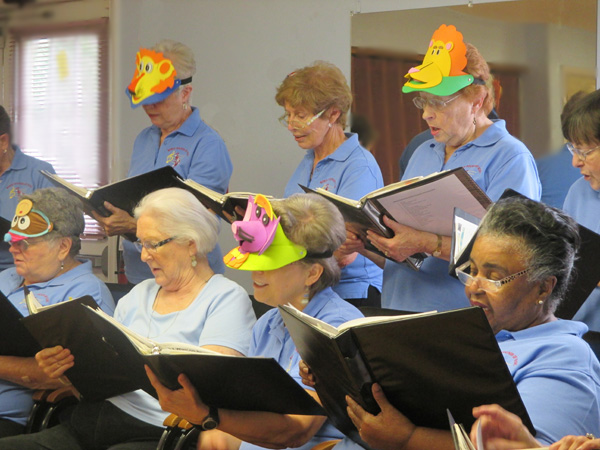 Photo shows a close-up of some of the singers wearing hats that are masks of cartoon animals