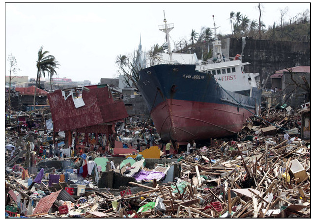 Photo shows a large boat sitting on top of the ruins and debris of homes in the Phillipines.