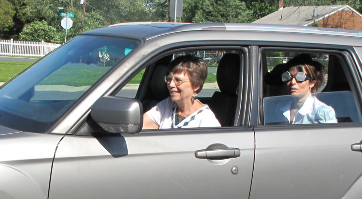 Photo shows Paul and Jomania wearing occluders and sitting in the back seat of a car while Dona drives.