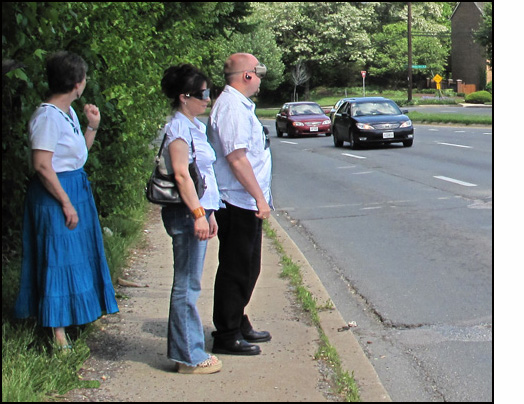 Photo shows two students listening to two cars approaching in the second lane, and Dona is behind them without indicating which lane they are in.