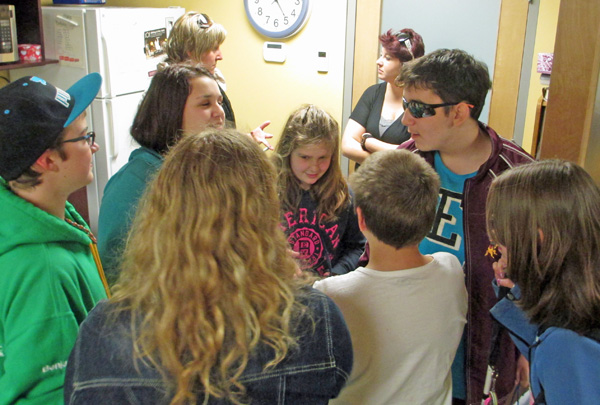 These 5 photos show the students greeting each other, sitting and standing around the conference table talking, and huddled together for a group hug.