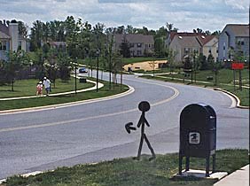 Photo shows a stick figure standing next to a mailbox at a T-intersection, facing a two-lane residential street that goes around a gentle curve to the right.  Beside the figure is the intersecting street, which has a stop sign.