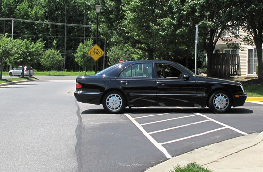 3 photos each show a car across the crosswalk -- the first is entering the far side of the side street, the second is coming out of the side street, and the third is going into the near side of the side street.