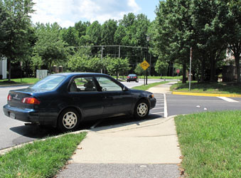 3 photos each show a car across the crosswalk -- the first is entering the far side of the side street, the second is coming out of the side street, and the third is going into the near side of the side street.