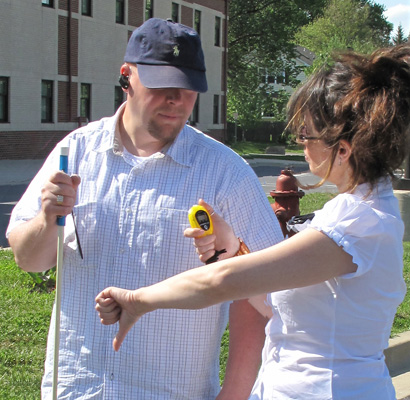 Photo shows a close-up of the instructor looking at her stopwatch and giving the student a 'thumbs-down' sign